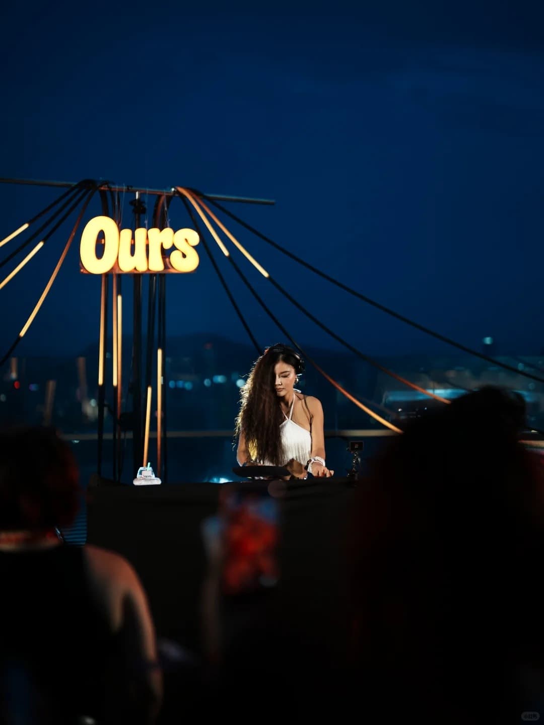 A DJ at an Ours rooftop party at dusk